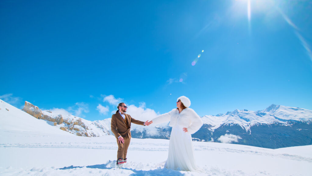 Marié ce tenant la main sous le soleil dans la neige à la montagne